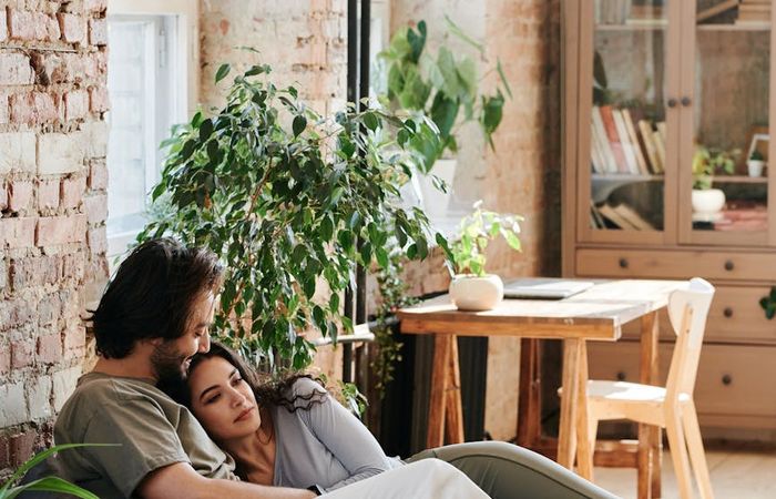 Person meditating in a bright, sunlit room with plants.